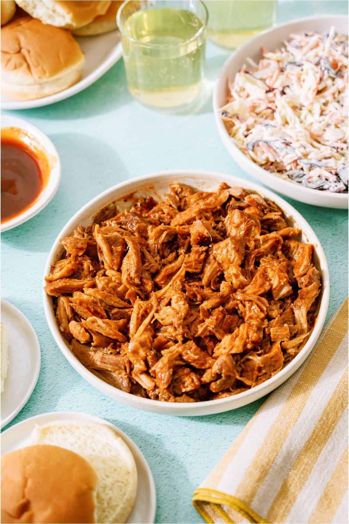 A bowl of Pulled Pork with a bowl of Coleslaw in the background.