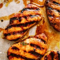 Grilled pork chops with visible char marks and marinade, arranged on a parchment-lined surface.