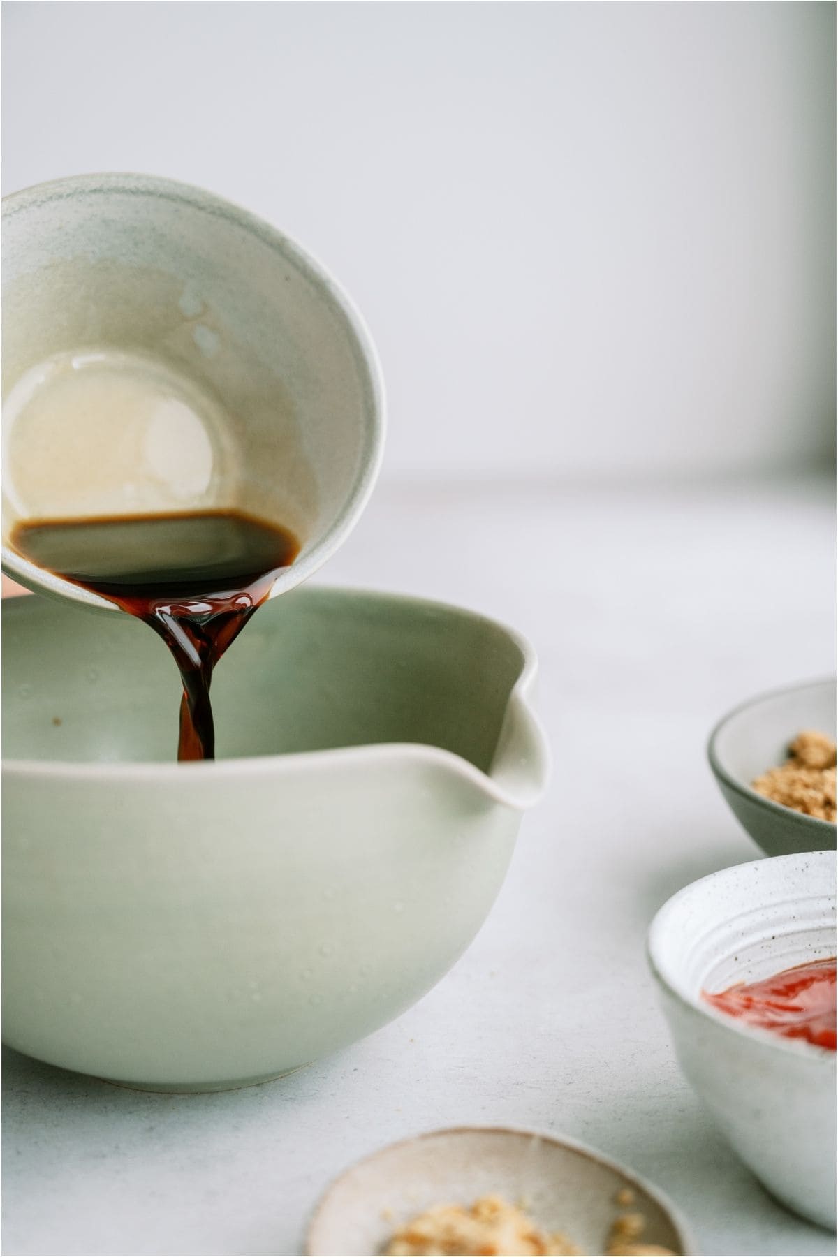 Pouring marinade ingredients into a white mixing bowl.
