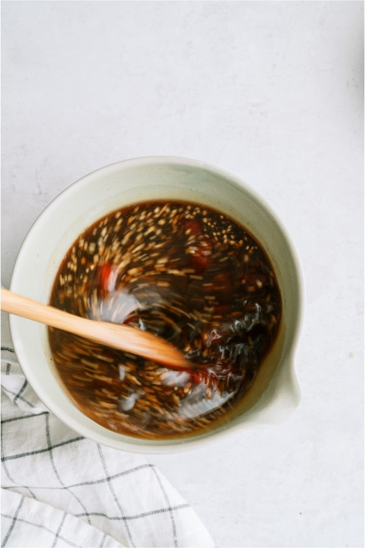 A wooden spoon mixing Huli Huli marinade together in a white bowl.