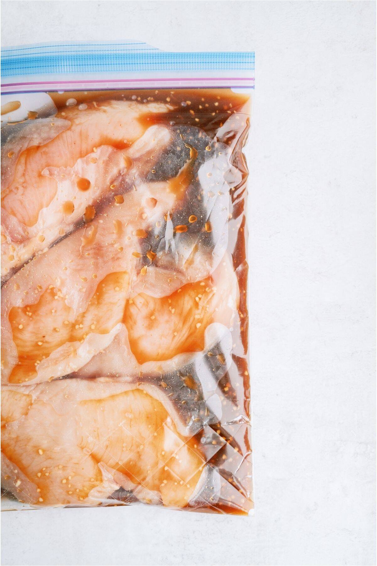 A ziploc bag full of chicken breasts with Huli Huli marinade.