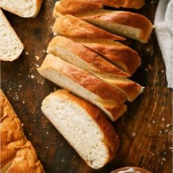 Homemade French Bread sliced on a cutting board with a small bowl of butter.