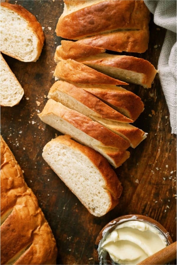 Homemade French Bread sliced on a cutting board with a small bowl of butter.