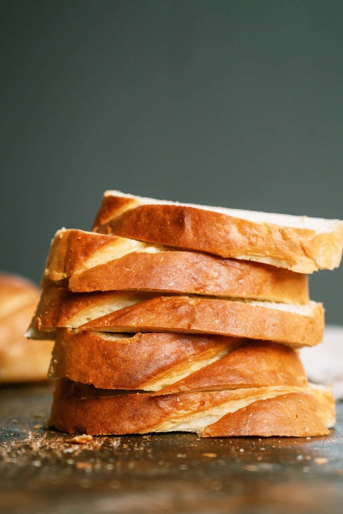Slices of Homemade French Bread stacked on a cutting board.
