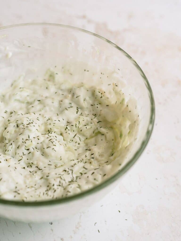 Homemade Tzatziki sauce in a glass mixing bowl.