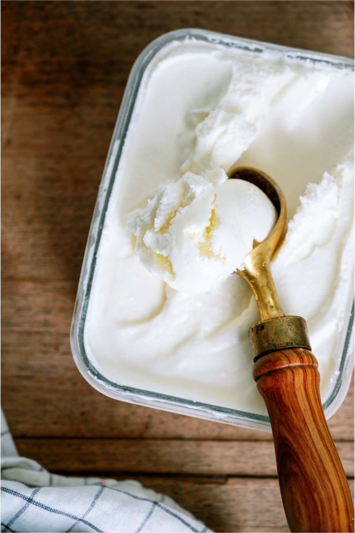 Ice cream container filled with vanilla ice cream and an ice cream scoop.