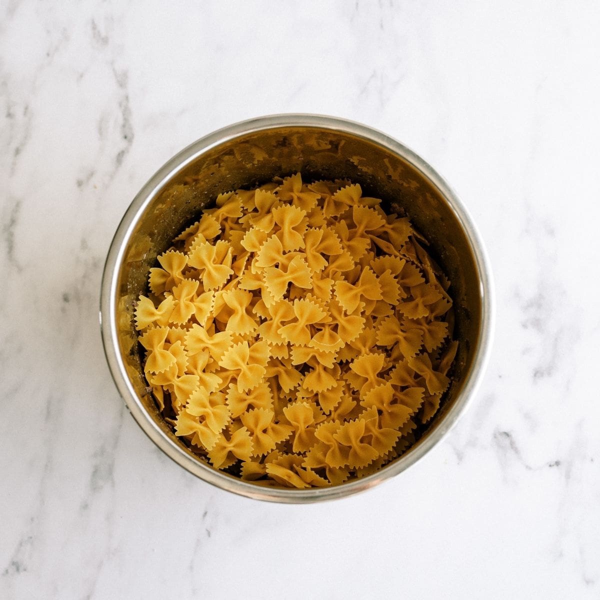 Bow tie uncooked noodles on top of cooked ground beef in instant pot