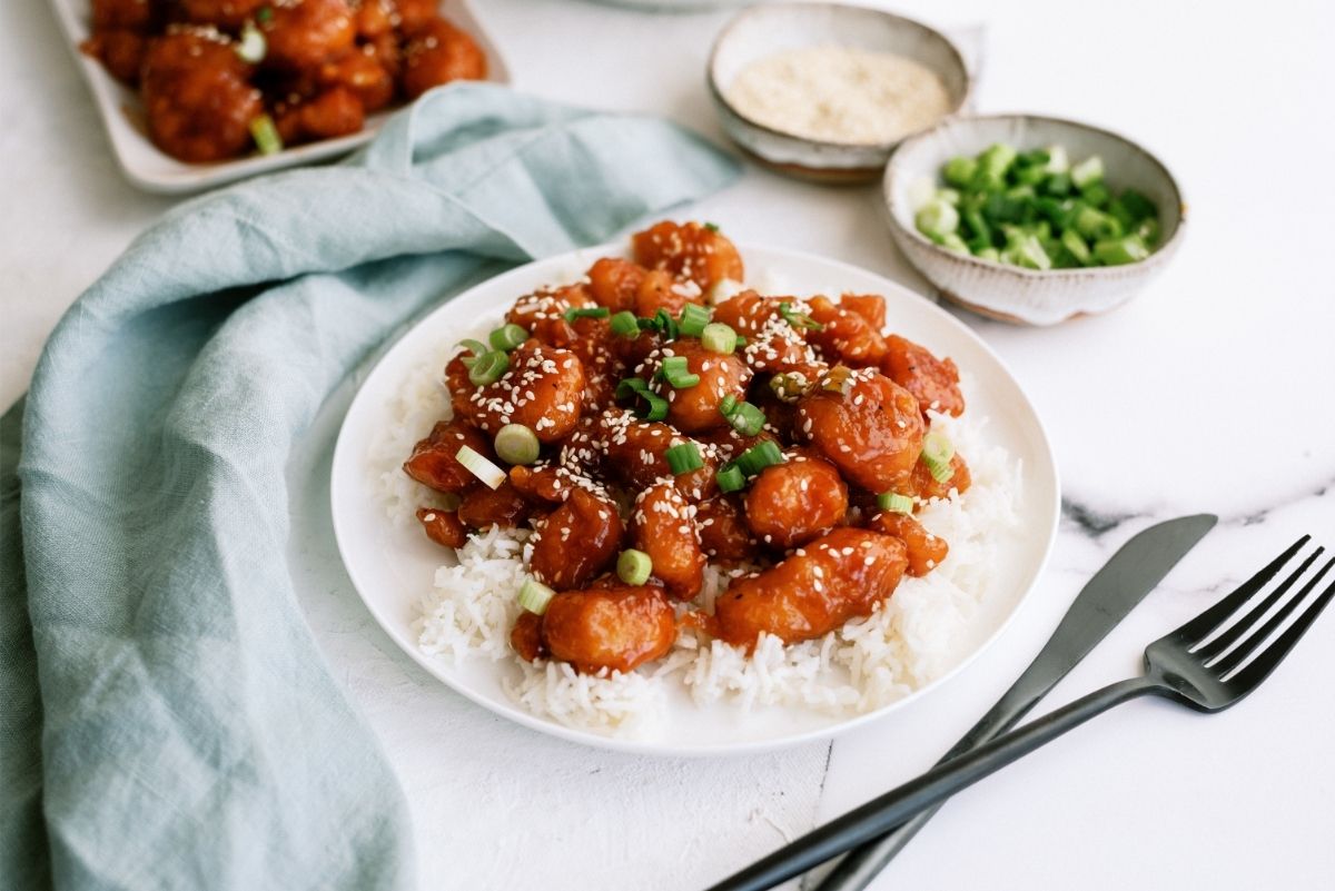 Instant Pot Sticky Chicken served over rice on white plate with fork and knife