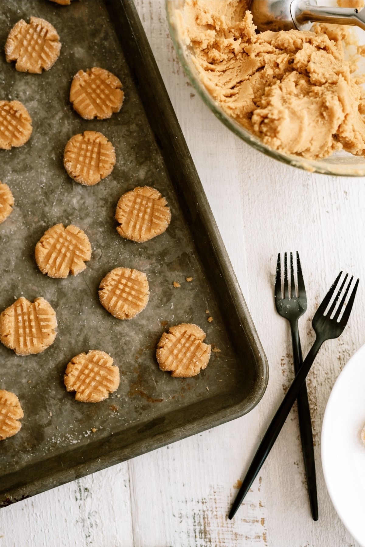 Peanut butter cookie dough smashed by forks on cookie sheet