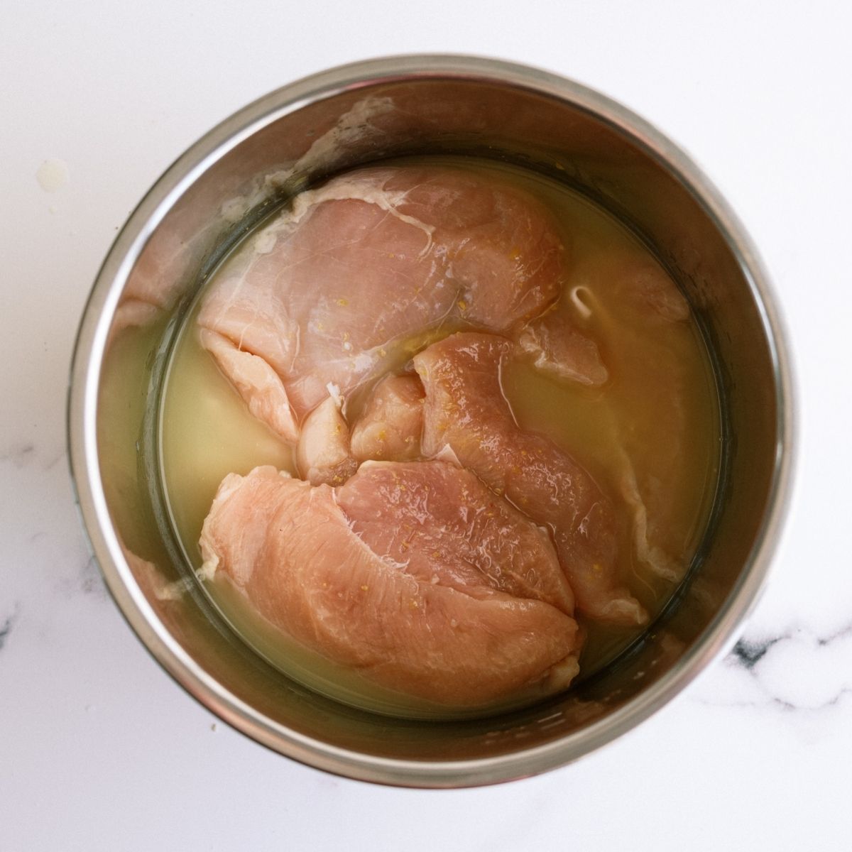 Raw chicken breast and chicken broth in Instant Pot