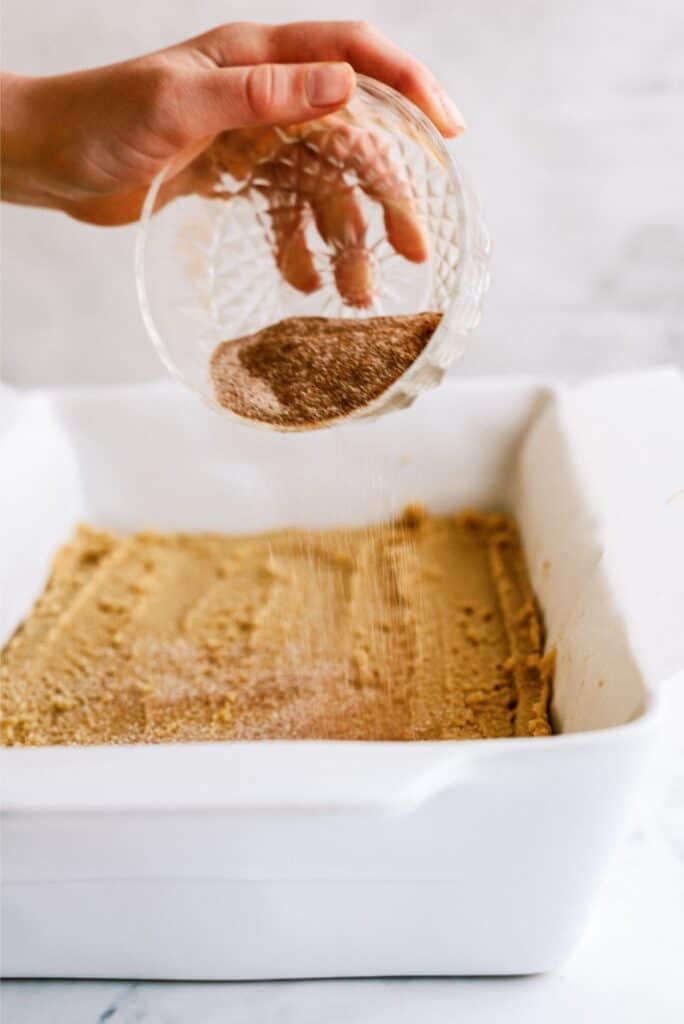 Sprinkling cinnamon and sugar mixture on top of Snickerdoodle Blondie dough.