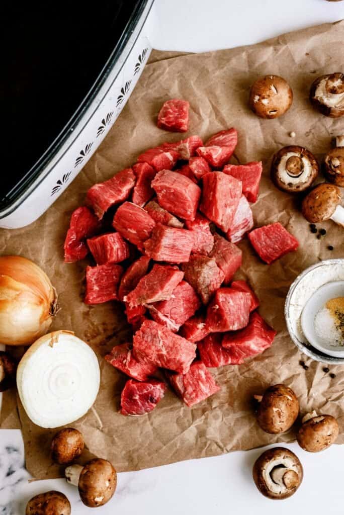 beef stew cubes ready to be added to instant pot with onions and mushrooms