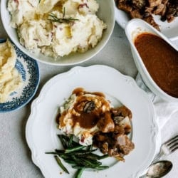Delicious beef tips with gravy and mashed potatoes on a white plate.
