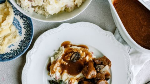 Delicious beef tips with gravy and mashed potatoes on a white plate.
