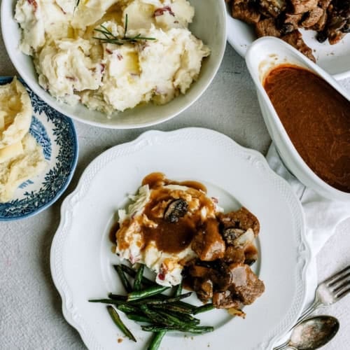 Delicious beef tips with gravy and mashed potatoes on a white plate.