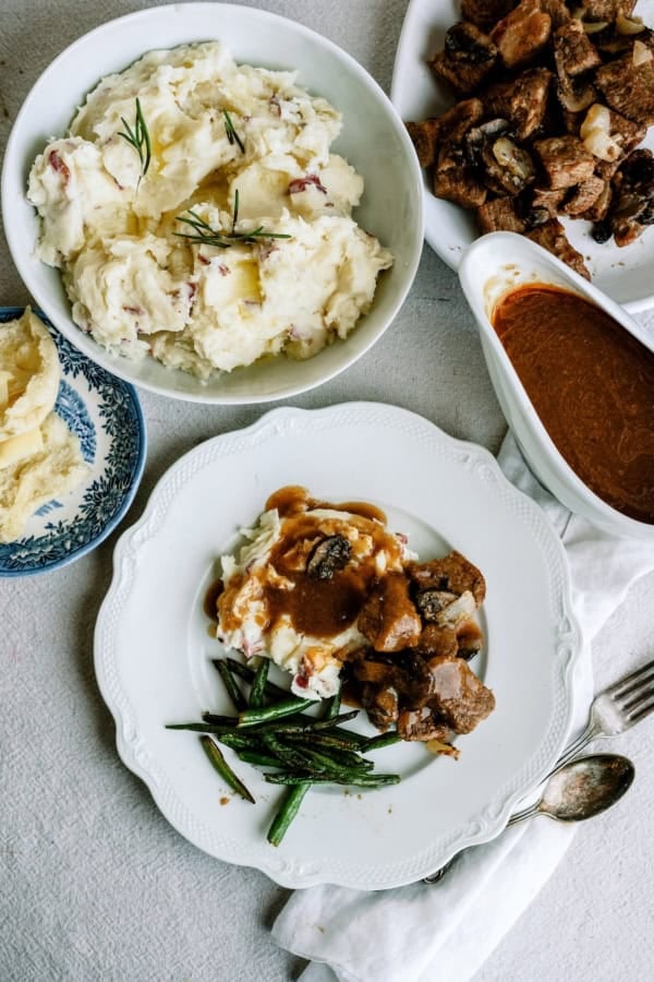 Delicious beef tips with gravy and mashed potatoes on a white plate.