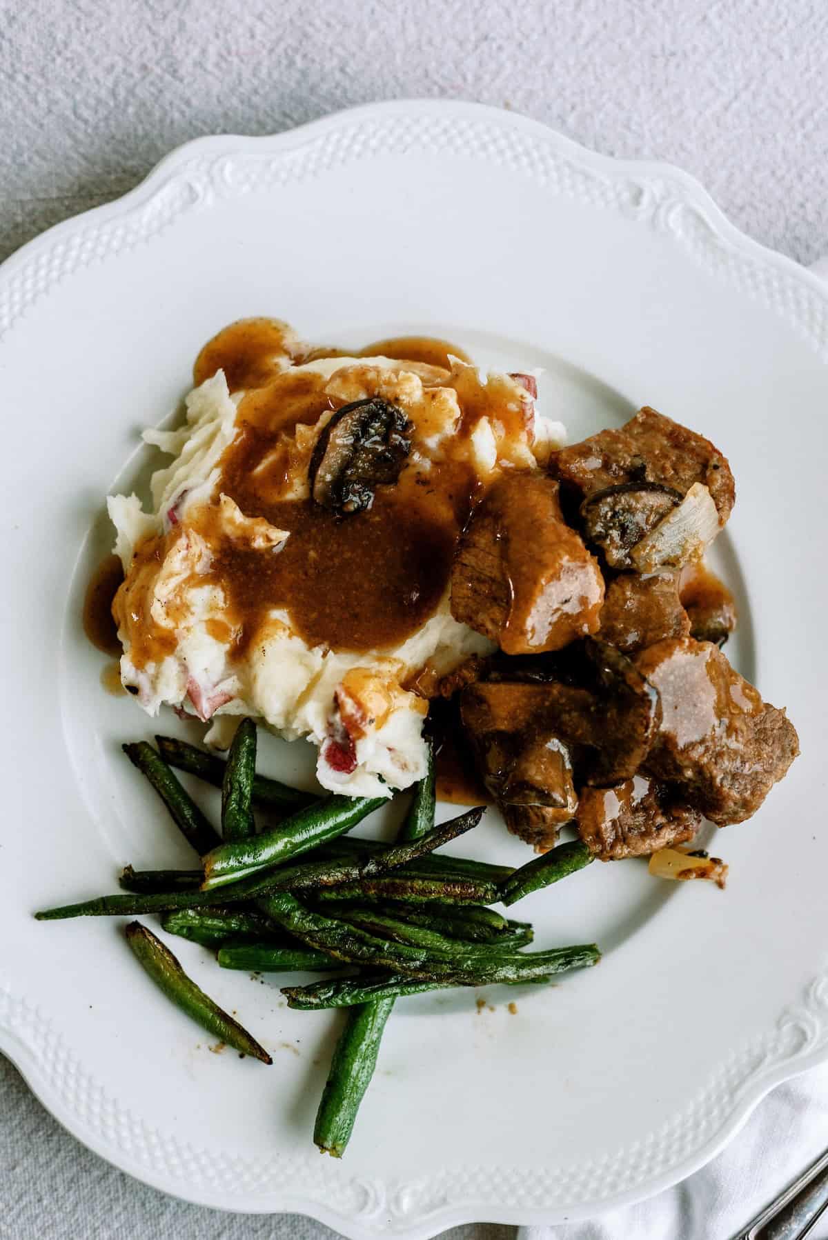 Delicious beef tips with gravy served with mashed potatoes and green beans.