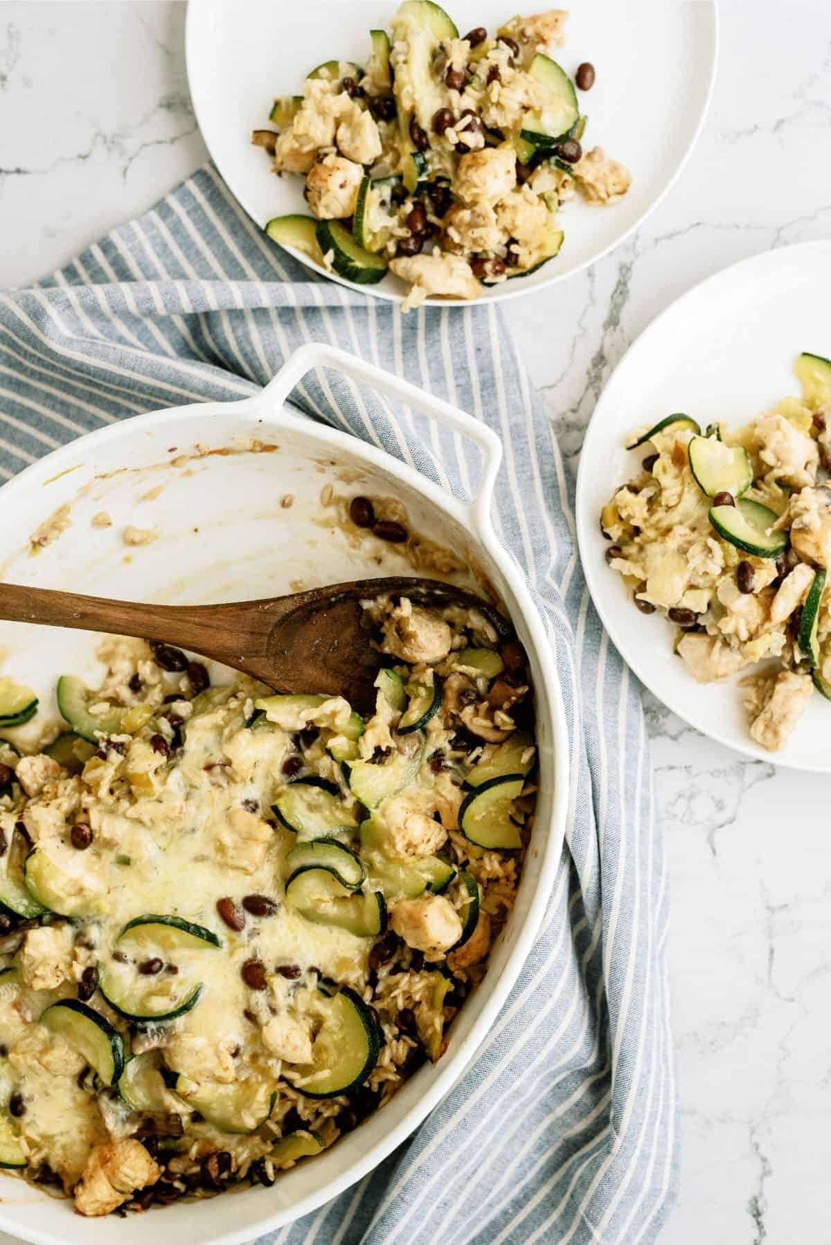 Baked Chicken and Black Bean Casserole in a white casserole dish with two servings on white plates