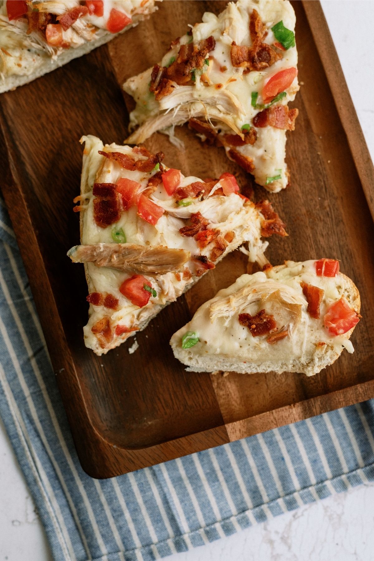 Chicken Bacon Alfredo French Bread Pizza cut into slices on a cutting board