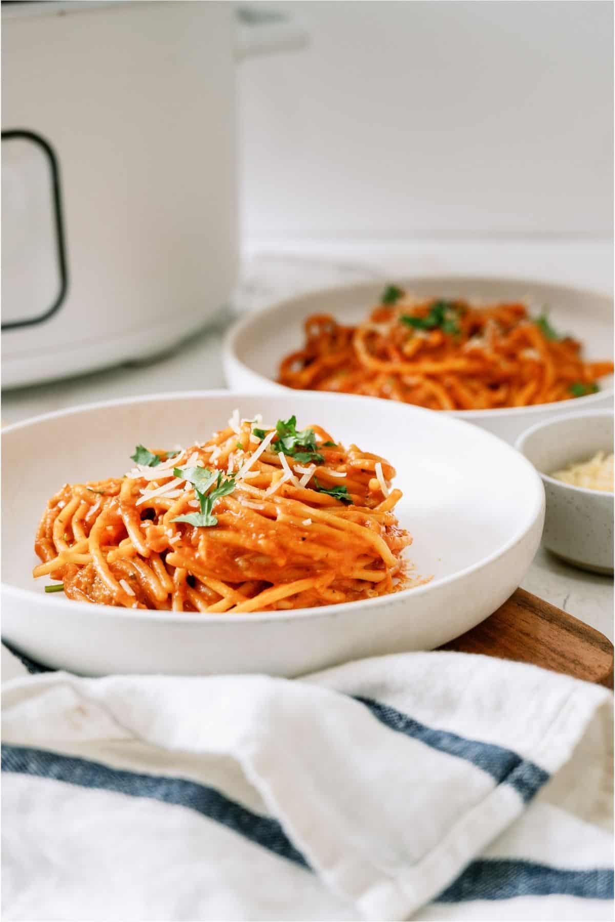 2 white plates with servings of Crock Pot Creamy Spaghetti on them.