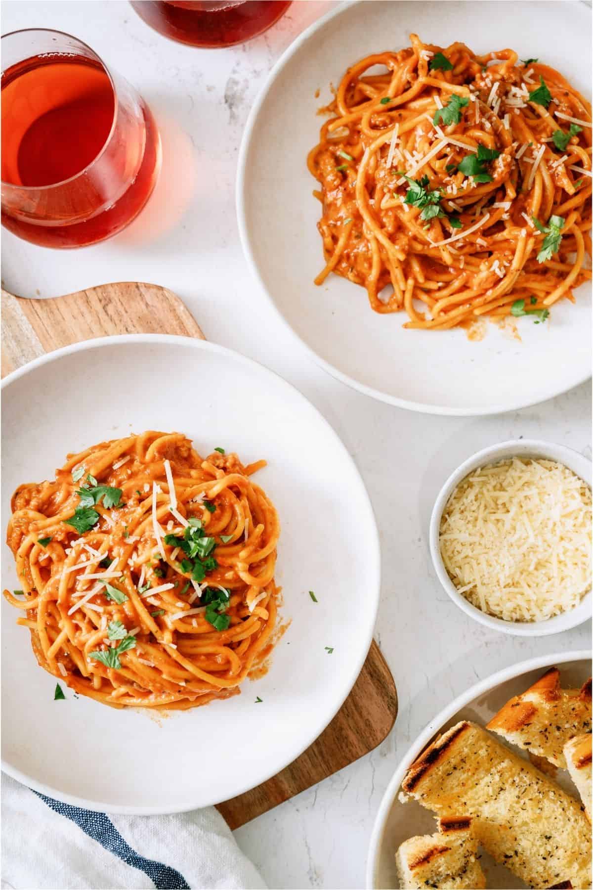 Top view of 2 white plates with servings of Crock Pot Creamy Spaghetti on them.