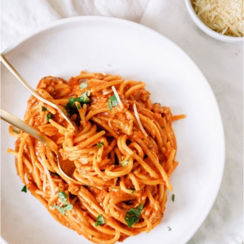 A serving of Crock Pot Creamy Spaghetti on a white plate with a fork.