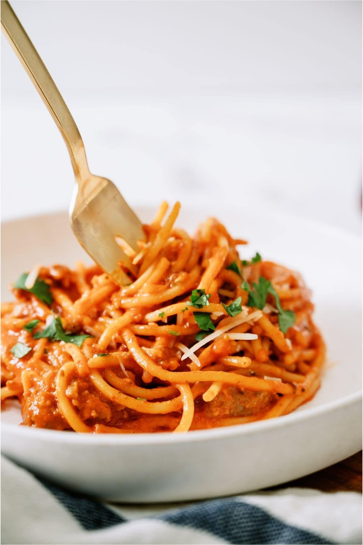 A fork with a serving of spaghetti on a white plate.