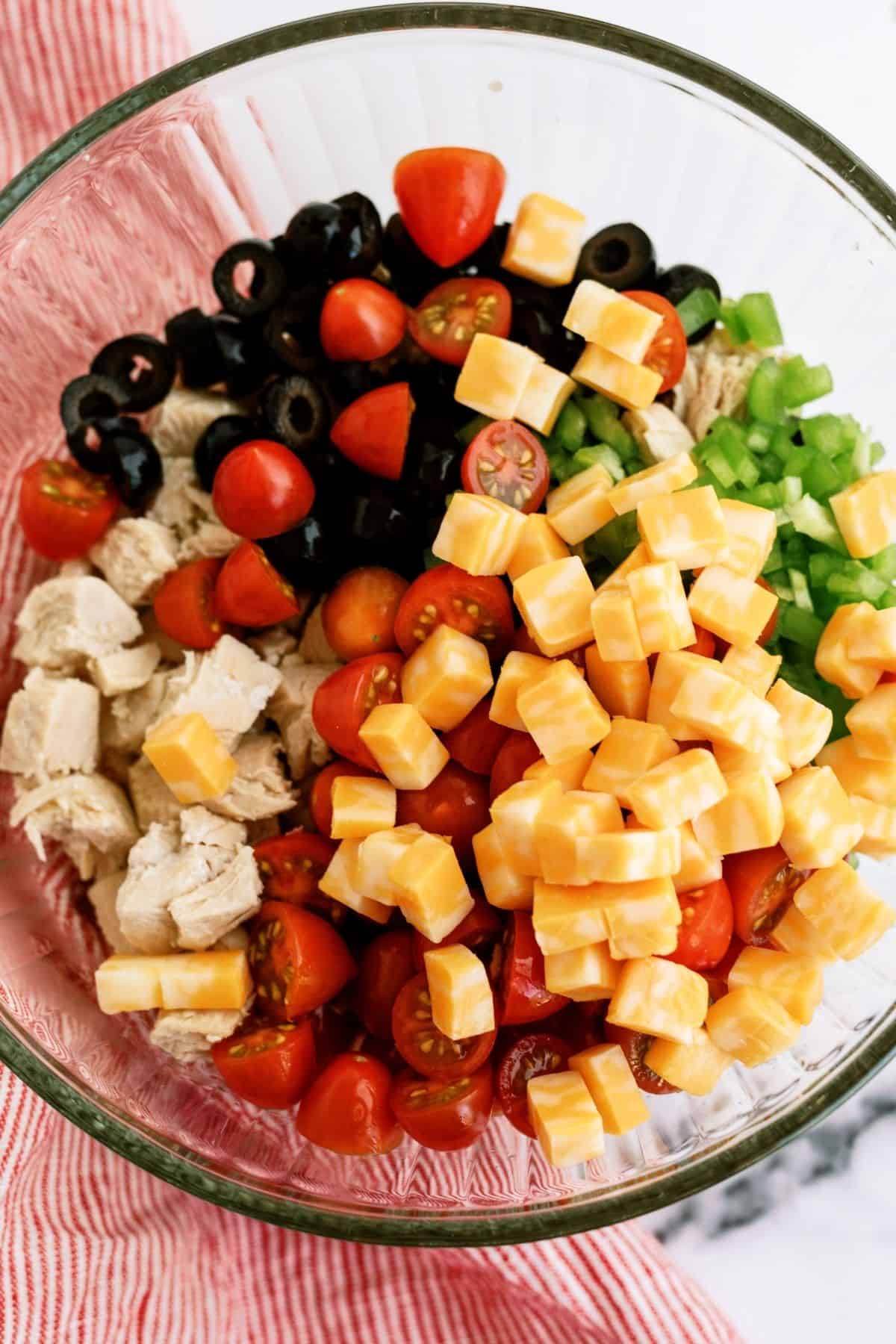 Ingredients for Grilled Chicken Bow Tie Pasta Salad mixed in a glass bowl