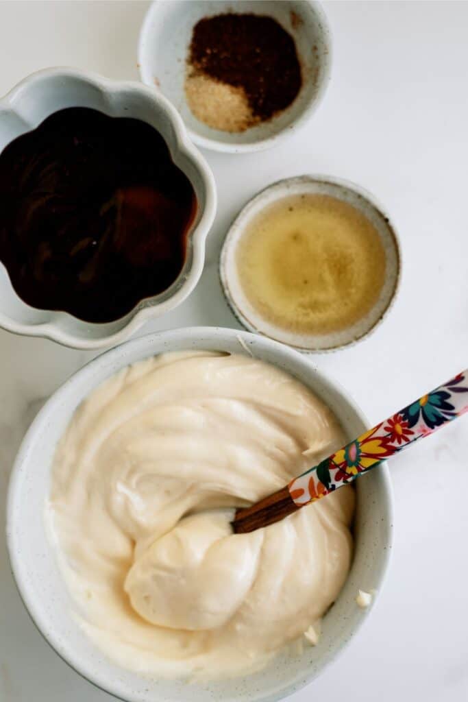 Bowls containing whipped cream, chocolate sauce, and pepper are arranged, with a decorative spoon in the cream bowl.