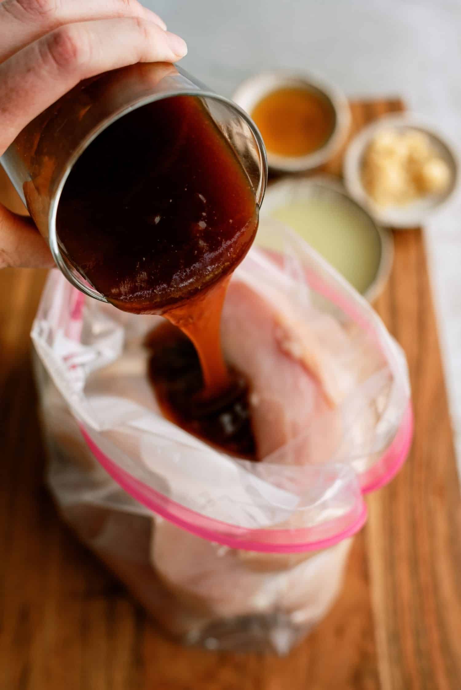 Pouring Marinade over chicken in ziploc bag