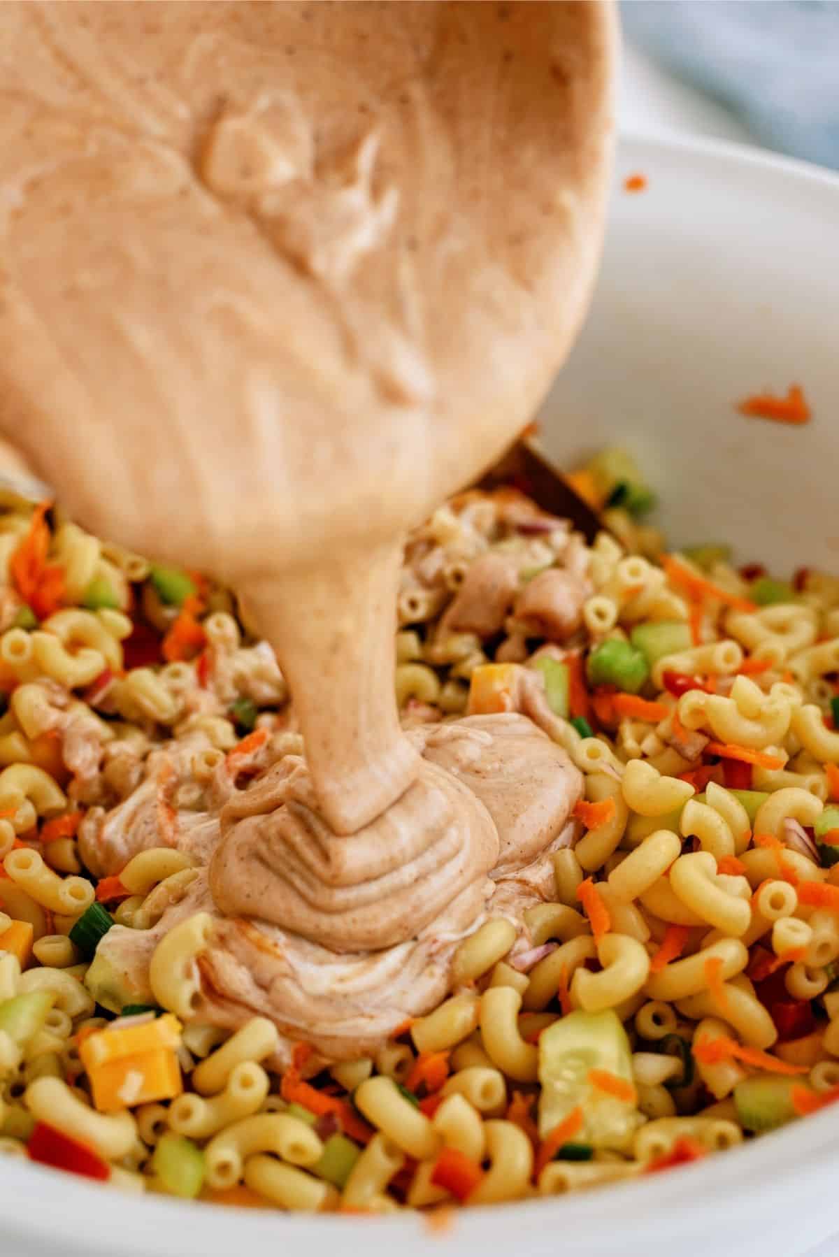 Pouring sauce on BBQ Macaroni Salad