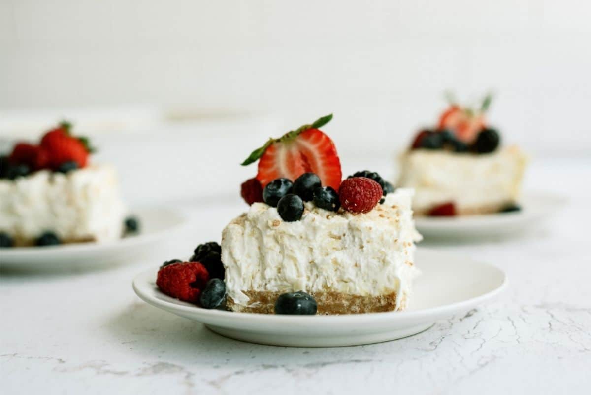 Sliced Fluffy Cream Cheese Dessert topped with berries on a plate