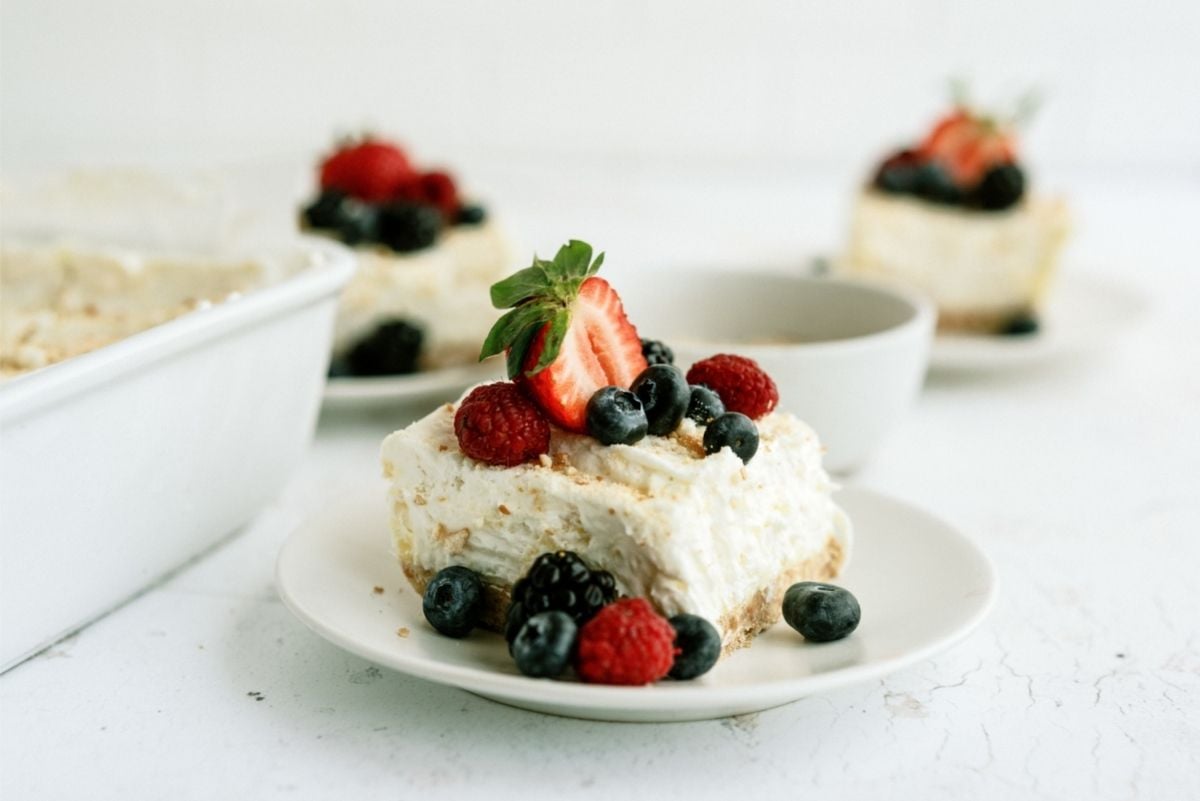 Sliced Fluffy Cream Cheese Dessert topped with berries on a plate