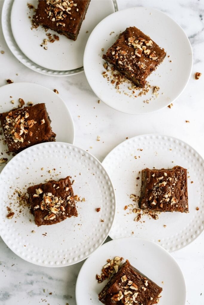 Top view of several slices of Snickers Cake on white plates.