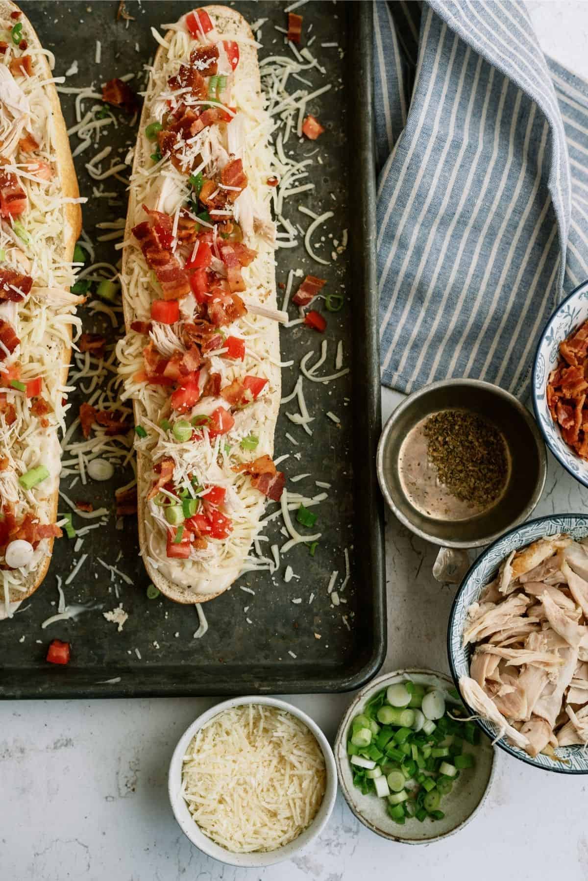 Unbaked Chicken Bacon Alfredo French Bread Pizza on a sheet pan