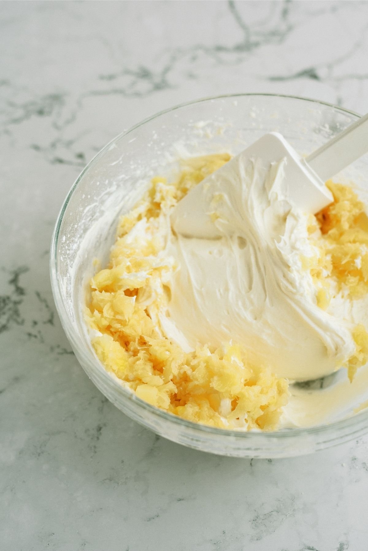 crushed pineapple added to cream cheese mixture in glass bowl