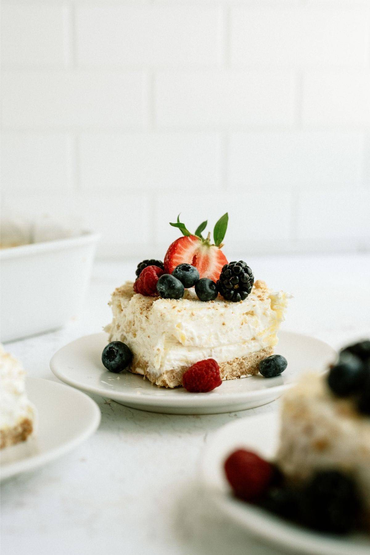 A slice of Fluffy Cream Cheese Dessert on a plate topped with berries.