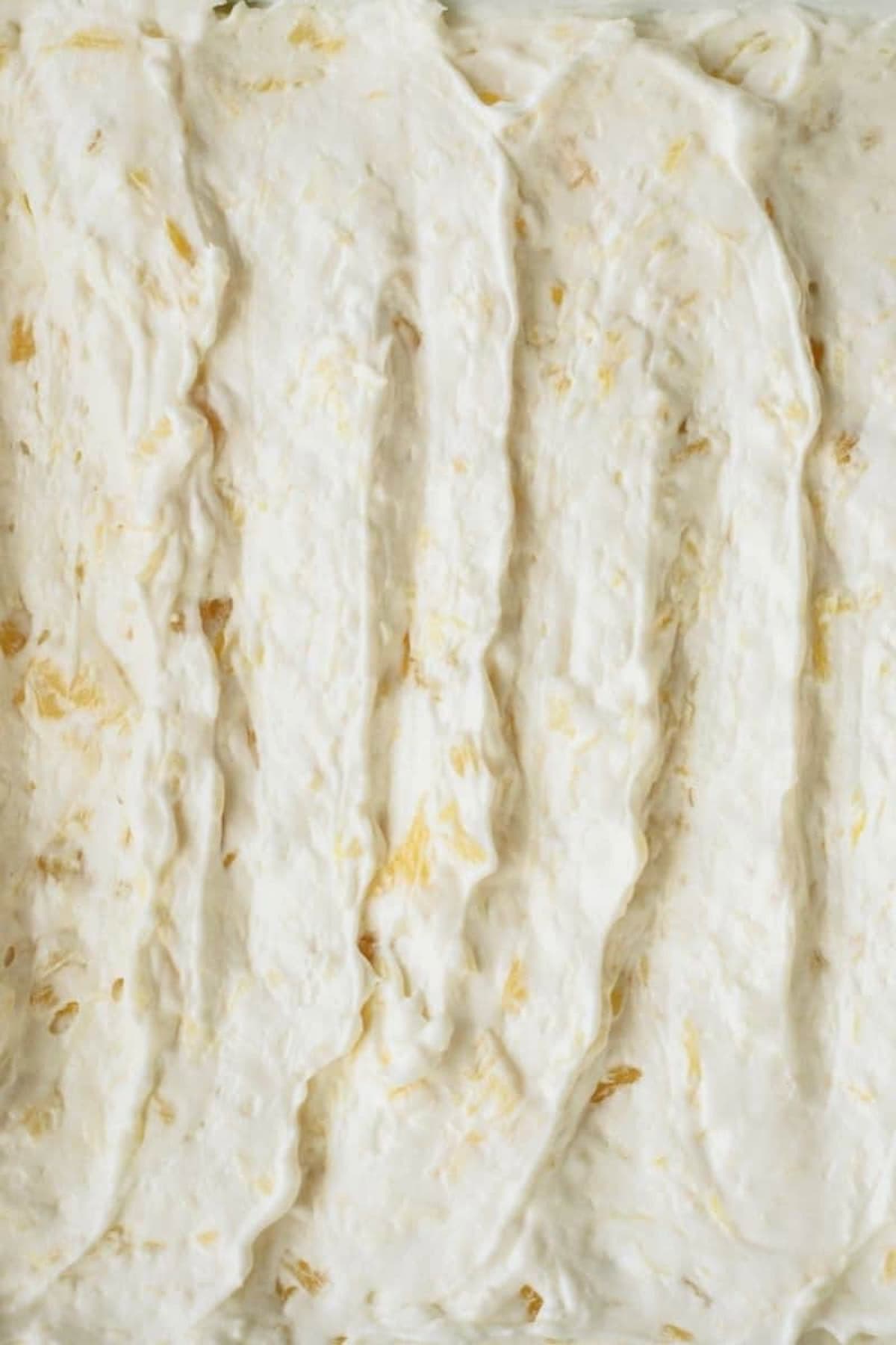 Close-up of a creamy, white mixture with visible small chunks, evenly spread in a baking dish.