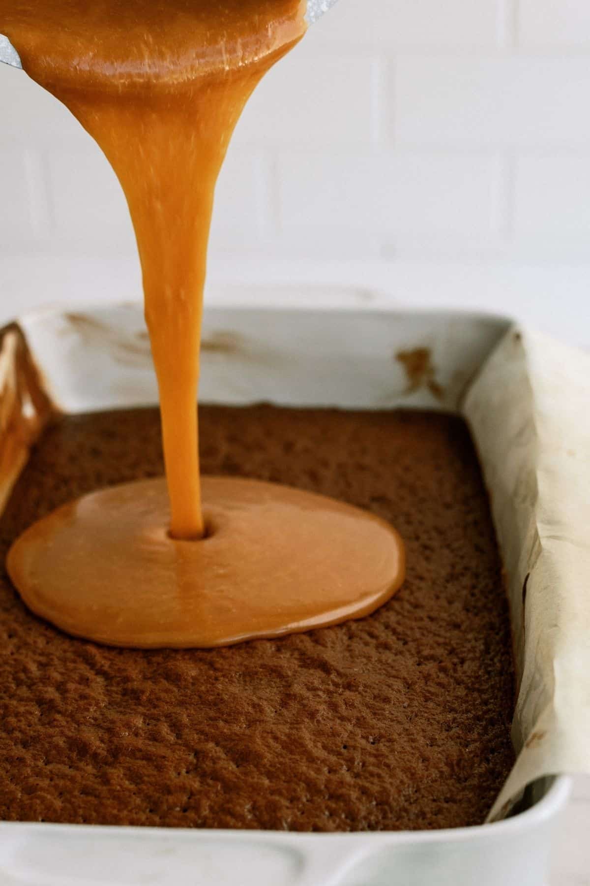 pouring caramel sauce on baked layer of cake