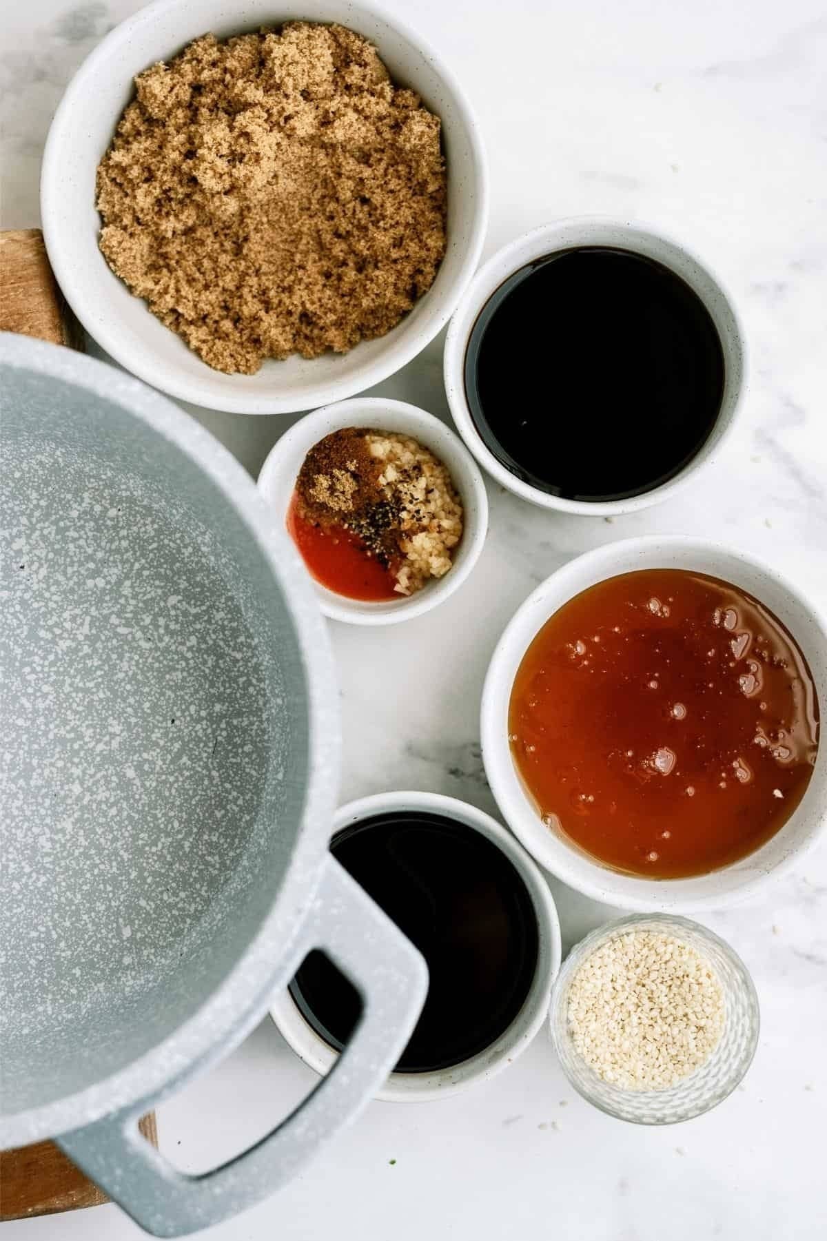 Ingredients in bowls include brown sugar, soy sauce, chili sauce, hoisin sauce, sesame seeds, and a spice mix, arranged beside an empty gray pot.