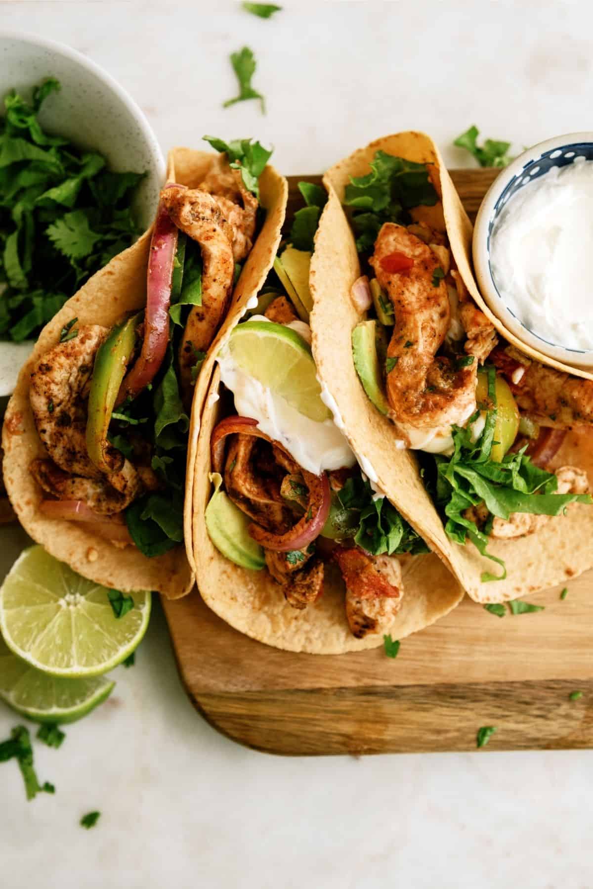 Baked Chicken Fajitas in tortillas, topped with a lime wedge and side of sour cream