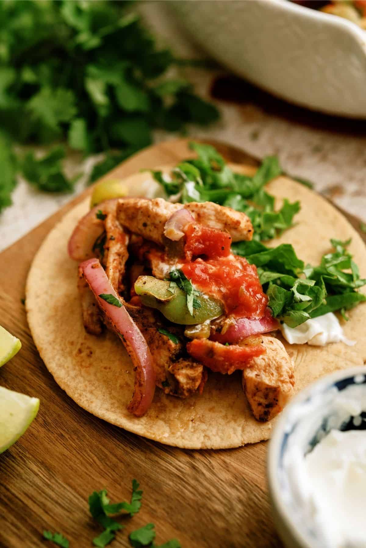 Baked Chicken Fajitas in a tortilla topped with cilantro, sour cream and salsa