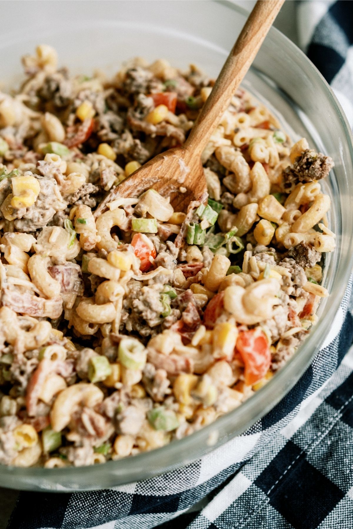 Cowboy Pasta Salad in a glass bowl with a wooden spoon