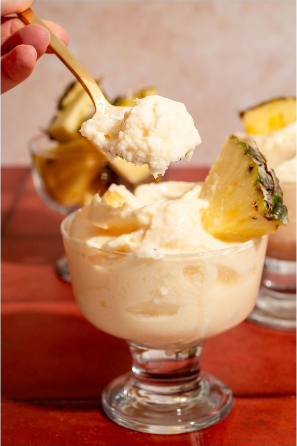 Front view of a spoon lifting out a bite of Disneyland Dole Whip out of a glass.