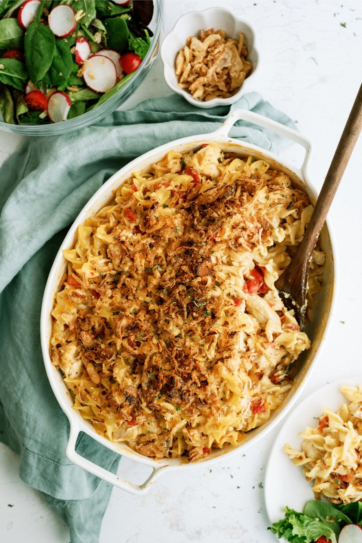 French Onion Chicken Noodle Casserole in a white casserole dish with a wooden spoon