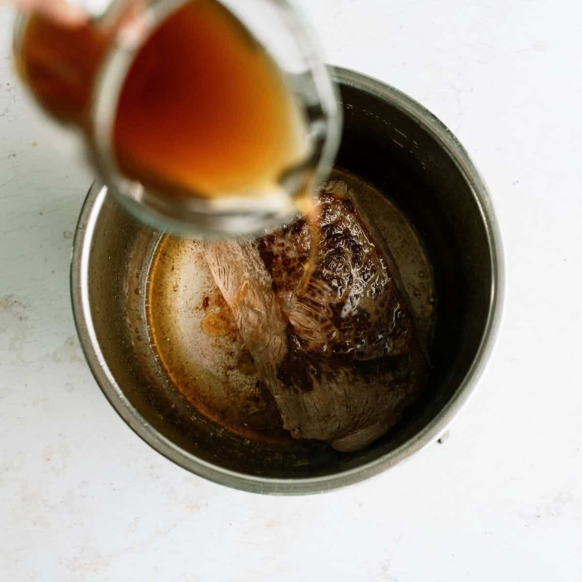 Pouring beef broth over Seared Roast in Instant Pot