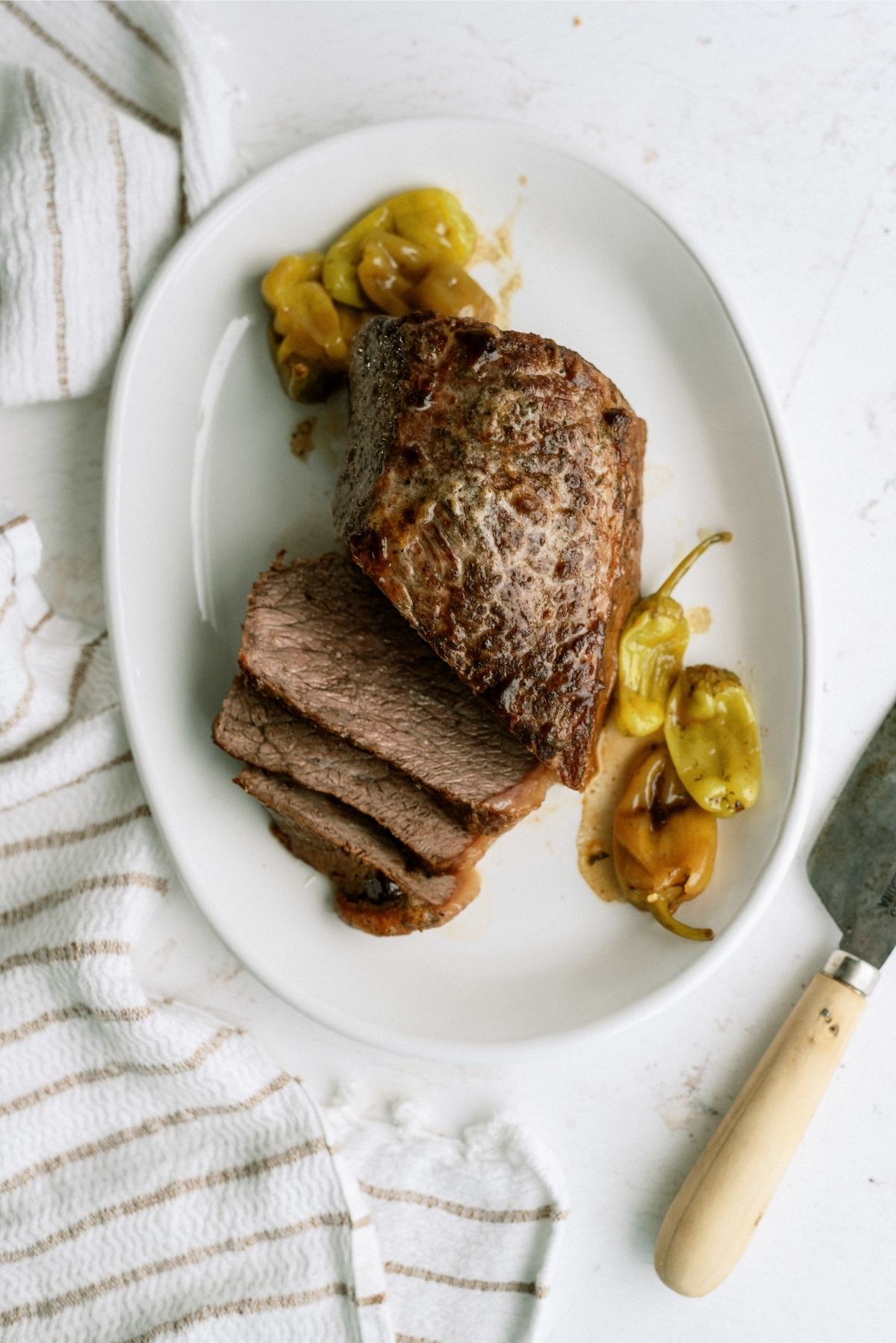 Instant Pot Mississippi Pot Roast sliced on a serving plate with pepperoncini peppers