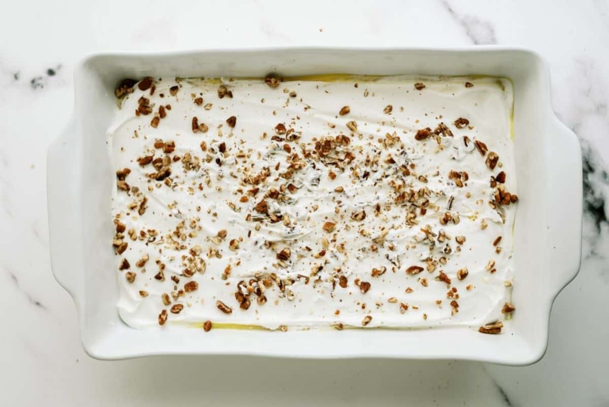 Layered Lemon Dessert with pecans sprinkled on top in baking dish