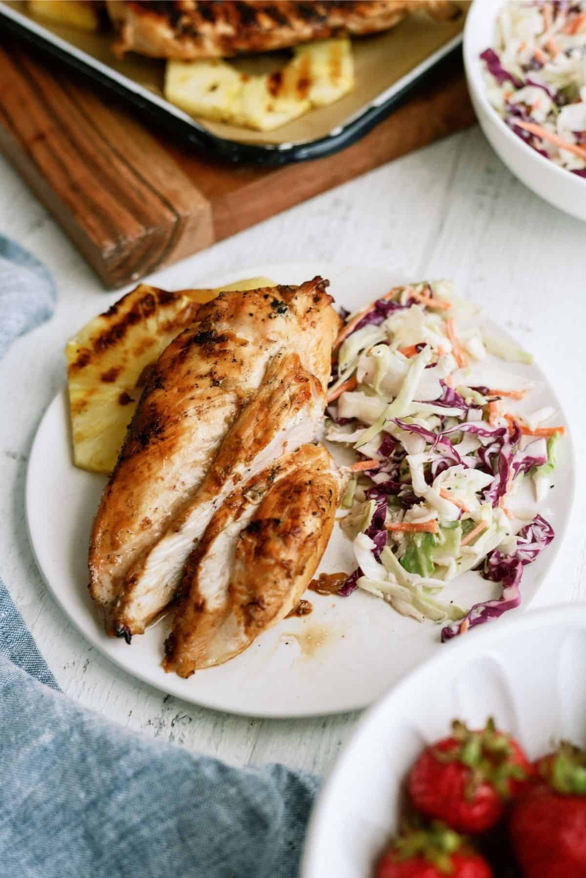 Pineapple Grilled Chicken sliced on a plate served with pineapple and coleslaw