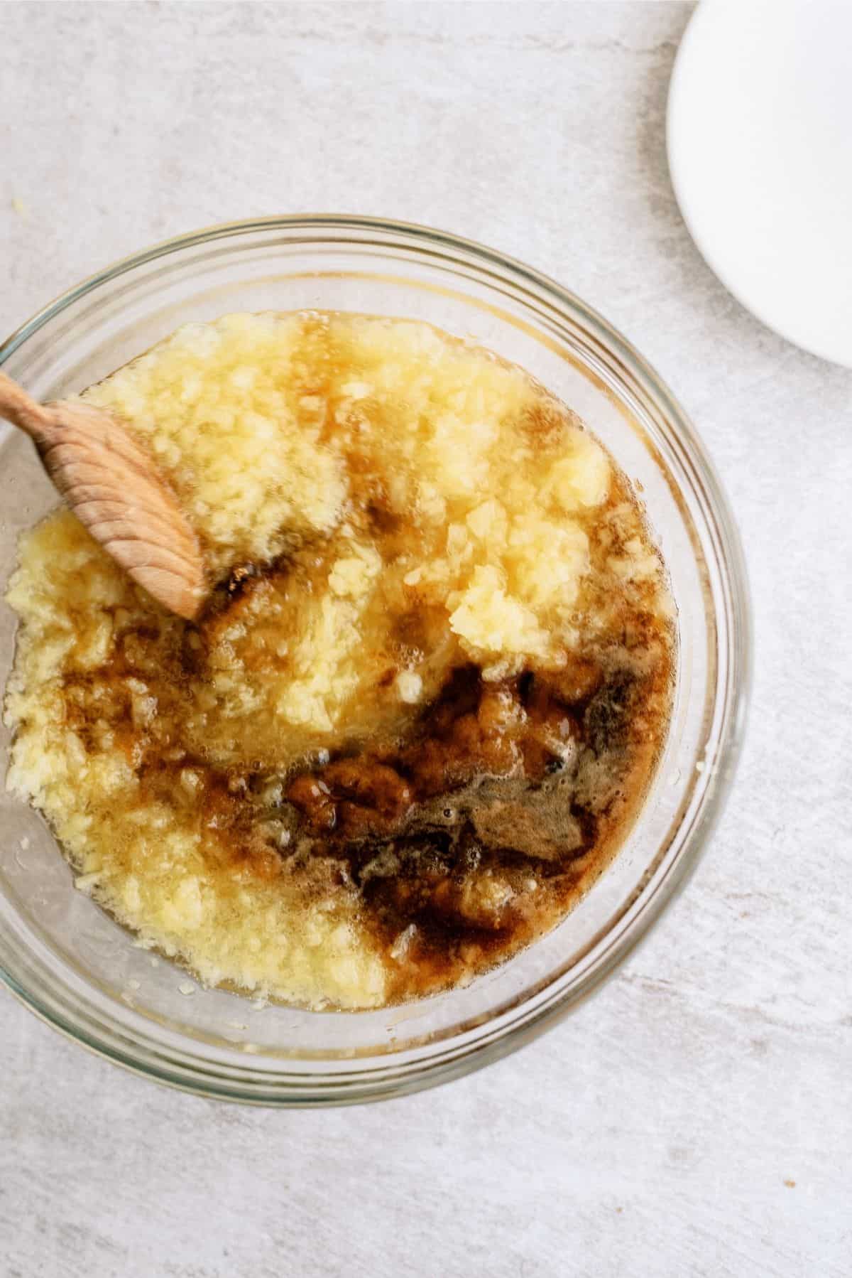 Pineapple Grilled Chicken marinade in a glass bowl, being mixed with a wooden spoon